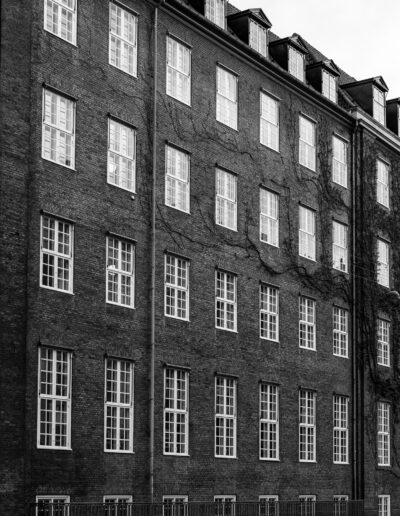 exterior of a brick building featuring a repeating pattern of white-framed windows, situated in Copenhagen Denmark