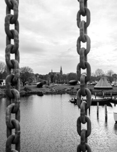 black and white photograph looking out over a calm body of water towards Rosklide Denmark skyline