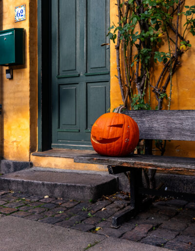 Halloween scene, a jack-o'-lantern displayed on a bench outside a house